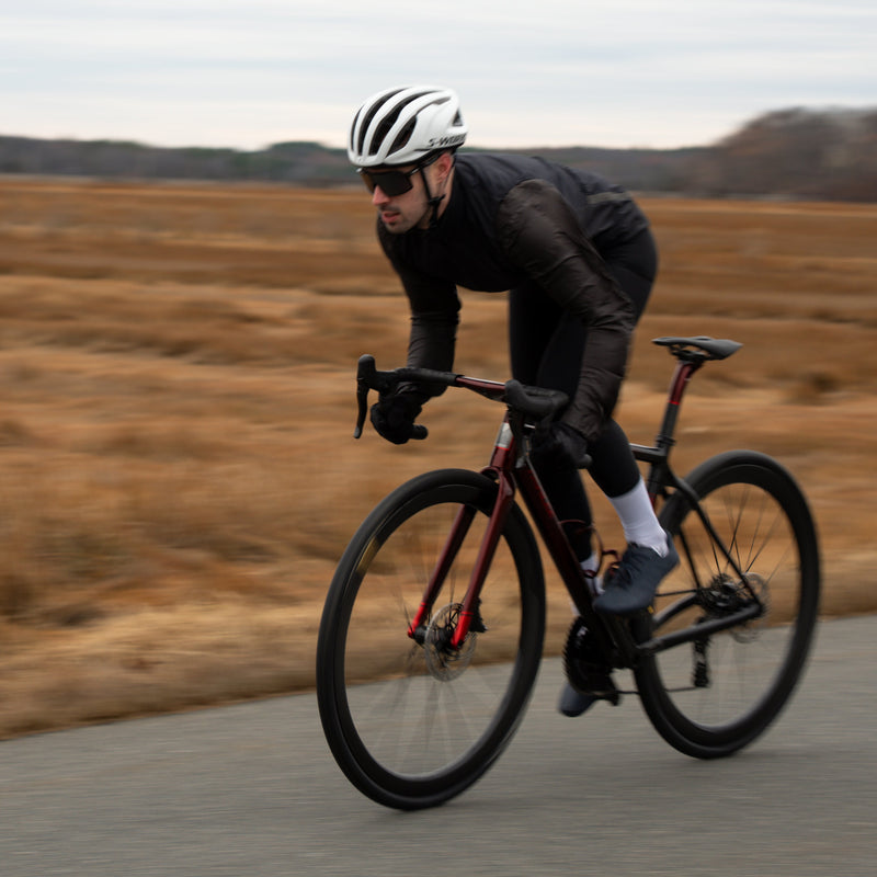 Person riding a bicycle on a road with a blurred natural background